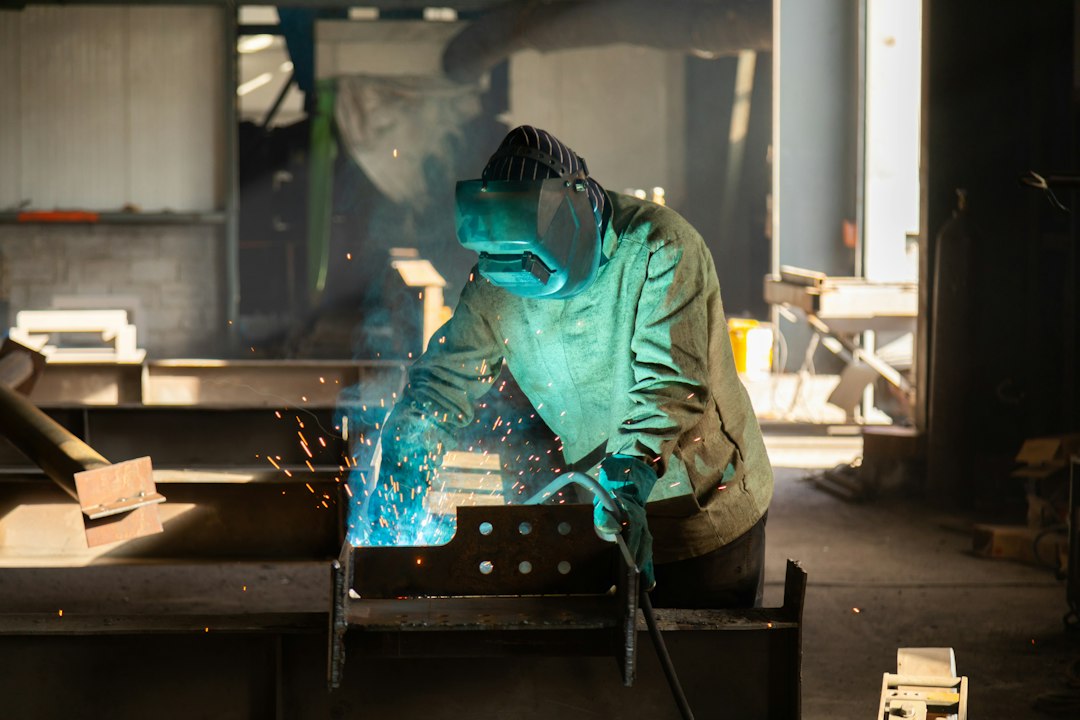 Industrial welder working on metal profiles in a fabrication hall; contextual image for stainless filler-metal guidance